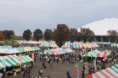 産業祭会場を上から見下ろしたところ。カラフルなしま模様のテントが並んでいる。背景はくまがやドームの白い屋根。