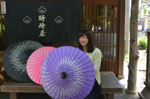 日陰で涼む女性。熊谷染めの日傘を持っている。