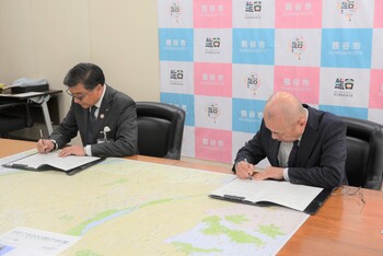 協定書にサインをする市長